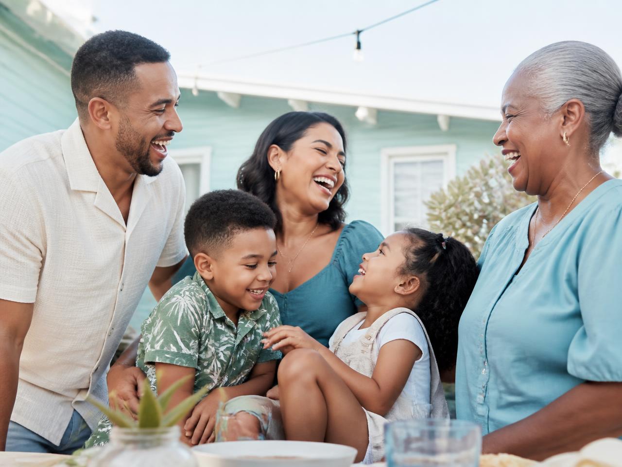 Three generations of a family laughing together outside their home